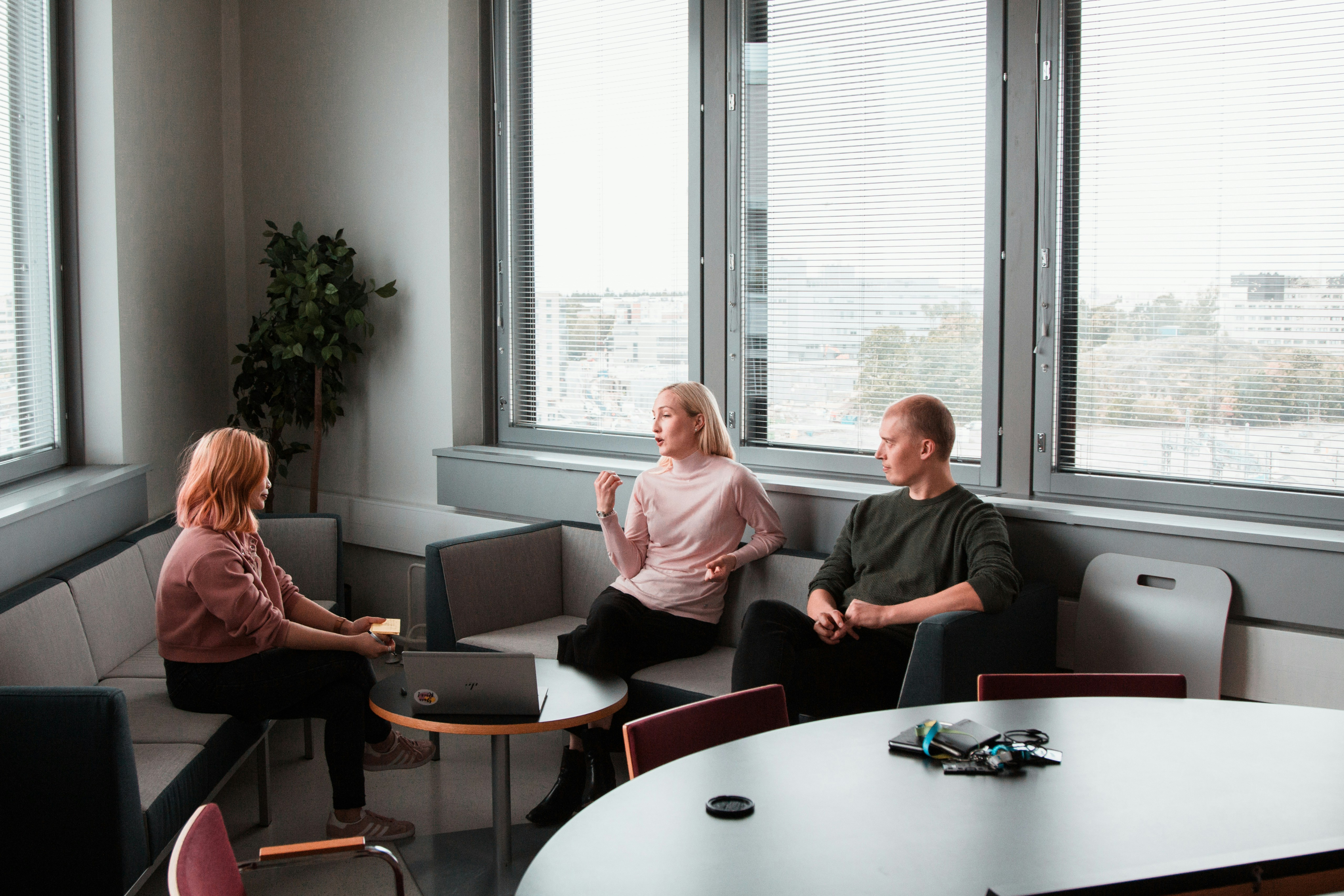 Photo of two women and a man talking in the corner of a room with modern furniture.